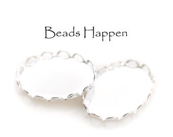 Pode incluir: Dois engastes de bisel de metal prateado com bordas festoneadas. Os engastes são projetados para segurar uma pedra redonda de cabochão.