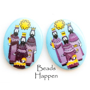 May include: Pair of oval-shaped ceramic earrings with a blue background and a depiction of the three wise men in purple robes, carrying gifts and following a yellow star.