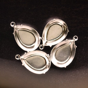 May include: Four silver-toned metal settings for attaching a pendant or charm. Each setting is shaped like a teardrop with a smooth, rounded edge and a small loop at the top.