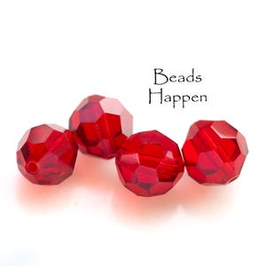 May include: Four red faceted glass beads, each with a unique shape and design. The beads are arranged in a cluster on a white background. The text "Beads Happen" is visible in the background.