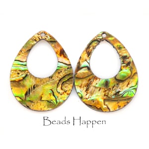 May include: Two iridescent abalone shell earrings with a teardrop shape and a hole at the top for hanging. The earrings are a light gold color with green and blue iridescent accents.