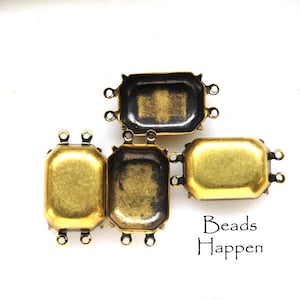 May include: Four gold-toned metal bezel settings with four loops on each side. The bezels are rectangular with rounded corners and have a slightly textured surface.