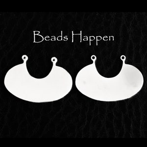 May include: Two silver metal pendant blanks with two holes at the top. The blanks are shaped like a crescent moon.