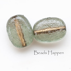 May include: Two frosted glass beads with a gold stripe running through the center. The beads are light green in color and have a textured surface.