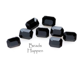 May include: Eight black rectangular glass beads, with a slightly beveled edge, are scattered on a white surface. The text "Beads Happen" is printed below the beads.