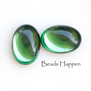May include: Two oval-shaped green glass beads. The beads are smooth and translucent.
