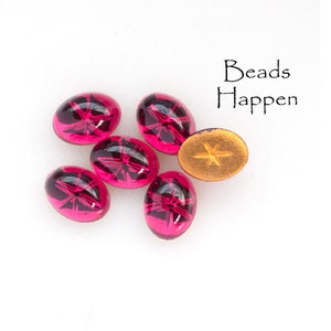May include: Six pink oval-shaped glass beads with a star-shaped design inside. The beads are on a white surface. The text "Beads Happen" is in the top right corner of the image.