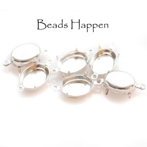 May include: Six silver oval-shaped metal settings with prongs on the bottom and two loops on the side.  The settings are for attaching cabochons or other flat-backed stones.