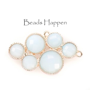 May include: Gold-toned metal charm featuring a cluster of seven white glass beads. The beads are round and have a faceted design. The charm has a loop at the top for attaching to jewellery.