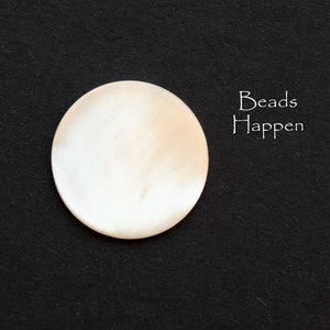May include: A white, round, smooth, and shiny bead. The bead is on a black background. The text "Beads Happen" is written in white on the right side of the image.