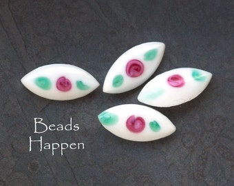 May include: Four white glass beads with pink and green floral designs. The beads are shaped like elongated ovals. The text "Beads Happen" is written in white on a dark gray background.