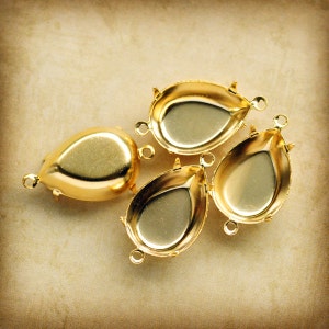 May include: Four gold-tone metal settings for attaching rhinestones or other embellishments. Each setting is shaped like a teardrop and has a flat back.