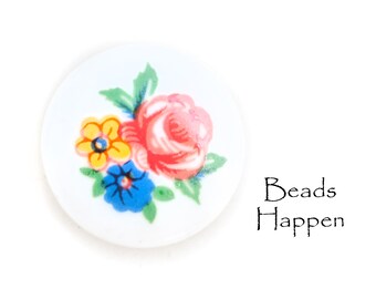 May include: White round button with a floral design featuring a pink rose, yellow flower, and blue flower with green leaves. The text "Beads Happen" is printed below the button.