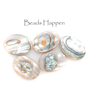 May include: Five oval-shaped iridescent beads with a pearlescent sheen. The beads have a mix of colors, including white, blue, and gold. The text "Beads Happen" is above the beads.