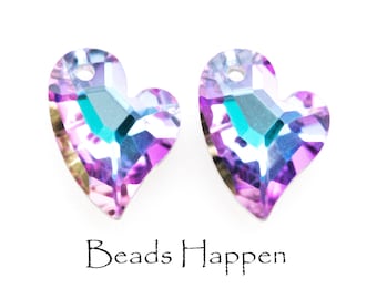 May include: Two iridescent purple and blue heart-shaped crystal beads with a hole for stringing. The beads have a faceted design and a teal-coloured centre.