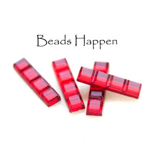 May include: Four red glass beads, each with a rectangular shape and a slightly raised, textured surface. The beads are arranged in a loose pile on a white background. The text "Beads Happen" is visible above the beads.