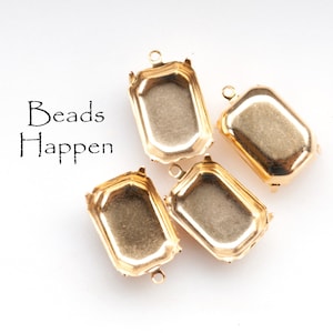 Puede incluir: Cuatro engastes de bisel de metal dorado para hacer joyas. Los engastes son rectangulares con esquinas redondeadas y tienen un acabado liso y brillante.  "Beads Happen" está escrito en texto negro sobre un fondo blanco.