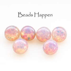 May include: Six iridescent pink and gold round glass beads. The beads have a speckled, glittery finish.