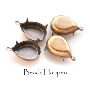May include: Four antique gold-toned metal teardrop-shaped pendant settings with prongs. The settings are designed to hold a cabochon stone.