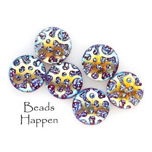 May include: Six iridescent glass beads with a gold and blue pattern. The beads have a textured surface and are arranged in a semi-circle on a white background. The text "Beads Happen" is printed below the beads.