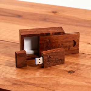 Puede incluir: Juego de memorias USB de madera y caja a juego. El juego de madera marrón oscuro presenta texto grabado que dice "Wedding" y "by". La memoria USB está enchufada y lista para usar.