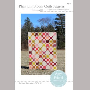 May include: A quilt pattern called "Phantom Bloom" with a geometric design in shades of pink, red, orange, yellow, and green. The quilt is laid out on a grassy field with trees in the background. The finished dimensions are 56 inches by 70 inches.