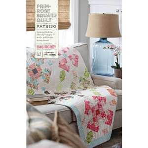 以下が含まれることがあります： BasicGreyによる「Prim-Rose Square Quilt」というキルトのパターンです。キルトはピンク、グリーン、ブルー、ホワイトの生地で作られています。キルトは、ランプと植物が置かれたソファの上に置かれています。