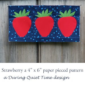 Peut inclure: Un bloc de courtepointe en patchwork de papier représentant trois fraises rouges avec des feuilles vertes sur un fond bleu à pois blancs. Le bloc mesure 4 pouces par 6 pouces. "Strawberry a 4" x 6" paper pieced pattern a During Quiet Time design" est écrit sous le bloc.