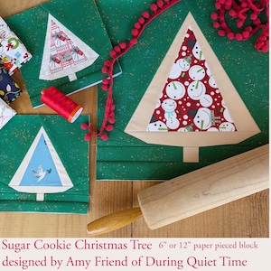 May include: A paper pieced Christmas tree block pattern with a green background and a beige tree with a snowman fabric inside. The text "Sugar Cookie Christmas Tree 6" or 12" paper pieced block designed by Amy Friend of During Quiet Time" is at the bottom of the image.