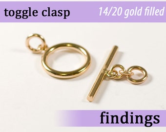 May include: Gold-filled toggle clasp for jewelry making. The clasp is made of 14/20 gold-filled metal and features a round ring and a bar with a small connecting ring.