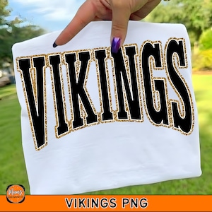 Könnte beinhalten: Weißes T-Shirt mit dem Wort "VIKINGS" in großen schwarzen Buchstaben, umrandet von goldenem Glitzer. Das T-Shirt wird von einer Hand gehalten. Der Text "VIKINGS PNG" befindet sich am unteren Rand.