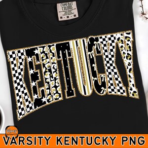 Peut inclure: T-shirt noir avec le mot "KENTUCKY" dans un style universitaire. Les lettres présentent divers motifs, notamment des carreaux noirs et blancs, un imprimé léopard doré et des rayures dorées. Le texte est souligné de paillettes dorées.
