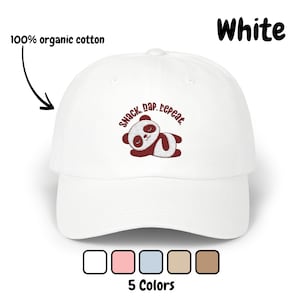 Può includere: Cappellino da baseball bianco con un panda ricamato e il testo "Snack. Nap. Repeat." Il cappello è realizzato in cotone biologico al 100%.