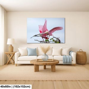 a large pink bird with outstretched wings perched on a branch, surrounded by greenery.