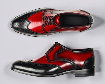 May include: Two-tone leather dress shoes. The shoes feature a wingtip design with black toe caps and heel counters, and a vibrant red vamp. The shoes are laced up and have a polished finish, suitable for formal occasions.