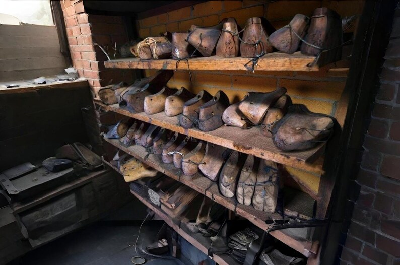 K&ouml;nnte beinhalten: Ein rustikales Holzregal mit verschiedenen antiken Schuhleisten. Die Leisten, in verschiedenen Formen und Gr&ouml;&szlig;en, sind aus dunklem Holz gefertigt und weisen Altersspuren auf. Die Regale stehen vor einer Backsteinmauer.