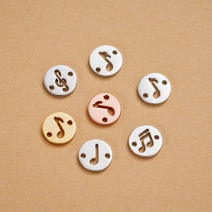 Puede incluir: Una colección de abalorios redondos de metal con diseños de notas musicales. Los abalorios están disponibles en varios acabados metálicos, incluyendo plata, oro y oro rosa. Cada abalorio tiene dos pequeños agujeros para ensartar.
