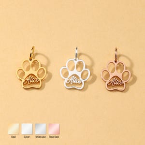 Puede incluir: Tres colgantes con forma de pata en oro, plata y oro rosa. Cada colgante tiene el nombre "Alice" en cursiva. Los colgantes se muestran sobre un fondo beige claro, con muestras de color etiquetadas como "Oro", "Plata", "Oro blanco" y "Oro rosa".
