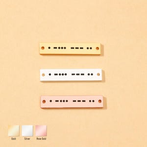 May include: Three rectangular metal bars in gold, silver, and rose gold, each with Morse code patterns. The bars have small holes at each end. The bottom of the image shows the color names: Gold, Silver, and Rose Gold.