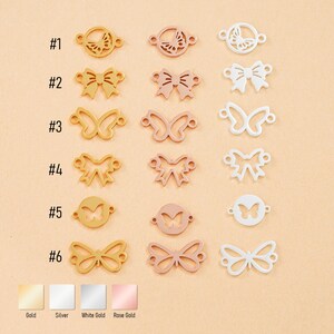 Peut inclure: Collection de breloques métalliques en forme de papillons et de nœuds, disponibles en or, argent, or blanc et or rose. Chaque breloque présente un design unique. Les breloques sont présentées sur un fond pêche clair.