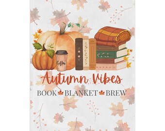 Könnte beinhalten: Eine weiße Decke mit einem Herbst-Design. Sie zeigt zwei Kürbisse, eine Kaffeetasse, Bücher und eine zusammengerollte Decke. Die Worte "Autumn Vibes, Book, Blanket, Brew" sind in einer dekorativen Schriftart geschrieben.