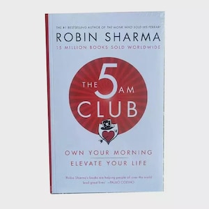 以下が含まれることがあります： ロビン・シャーマ著「The 5 AM Club」の表紙。赤い円の中に数字の5と「The 5 AM Club」という文字が白で書かれている。本のタイトルは「Own Your Morning, Elevate Your Life」。下部には「Robin Sharma's books are helping people all over the world lead great lives - Paulo Coelho」という引用文が書かれている。