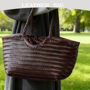 Può includere: Una borsa in pelle marrone intrecciata con manici intrecciati. La borsa ha una forma rettangolare con la parte superiore curva e una chiusura con coulisse. Il testo "LEATHER BAG" è nella parte superiore dell'immagine.