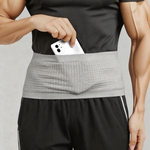 Puede incluir: Una riñonera gris con un diseño perforado se lleva alrededor de la cintura. Se está colocando un teléfono inteligente blanco en el bolsillo de la riñonera. El texto "FREE FOR FINE - FANNY PACKS" está en la parte superior de la imagen. La persona lleva una camiseta negra y pantalones cortos negros.