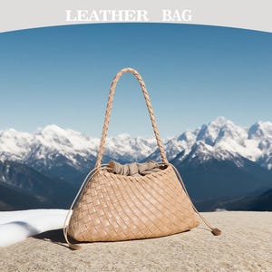 May include: A beige leather bag with a woven design, featuring a braided handle and drawstring closure. The bag is set against a backdrop of snow-capped mountains and a clear blue sky. The text "LEATHER BAG" is at the top.