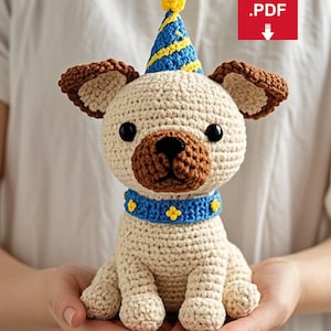 Puede incluir: Patrón de amigurumi de crochet para un perro beige que lleva un gorro de fiesta azul y amarillo con un pompón amarillo. El perro tiene orejas marrones, una nariz marrón y ojos negros. El perro lleva un collar azul con flores amarillas.