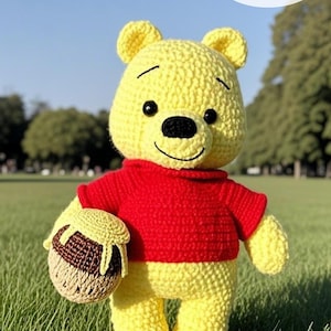 May include: A crocheted yellow bear wearing a red sweater, holding a brown and tan honey pot. The bear has black eyes and a stitched smile. The image includes text that says "CROCHET PATTERN instant download" with an American flag.