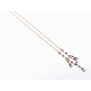 May include: A delicate gold chain necklace with a pendant featuring a cluster of blue and pink gemstones. The pendant is made up of several teardrop-shaped stones and smaller round stones.