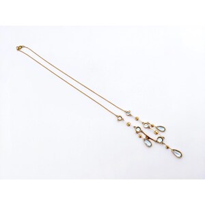 May include: A gold chain necklace with a pendant featuring multiple teardrop-shaped blue stones and small round gold beads.