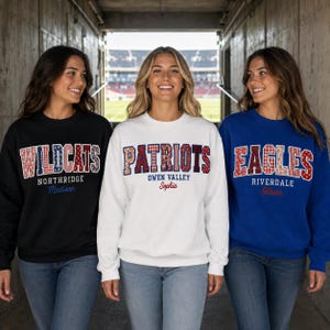 May include: Three crewneck sweatshirts in black, white, and blue. Each features a large collegiate-style word in a red, white, and blue patterned font, with a secondary school name and a personalised name printed in smaller text underneath.